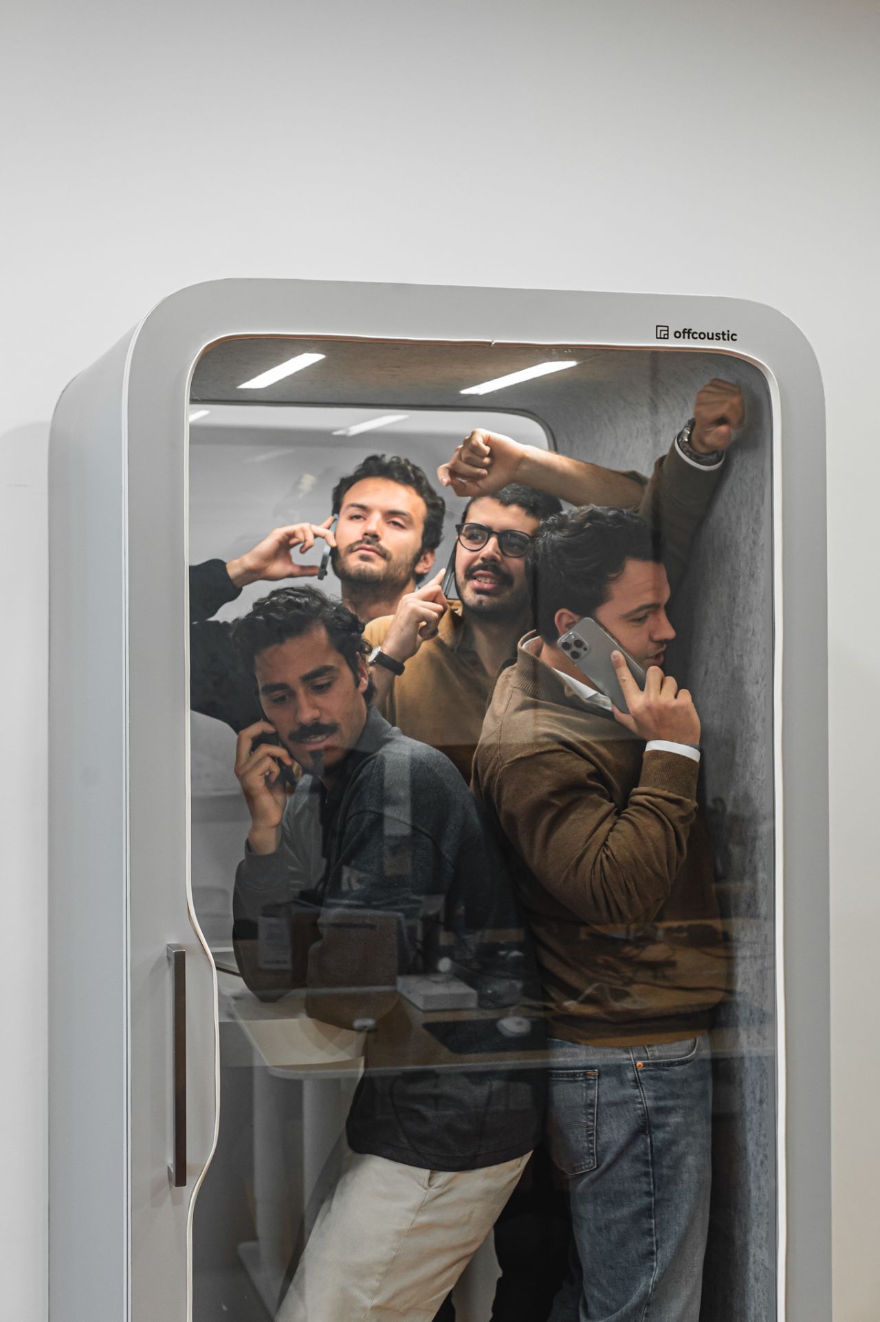 Four people crammed into an Offcoustic phone booth, laughing