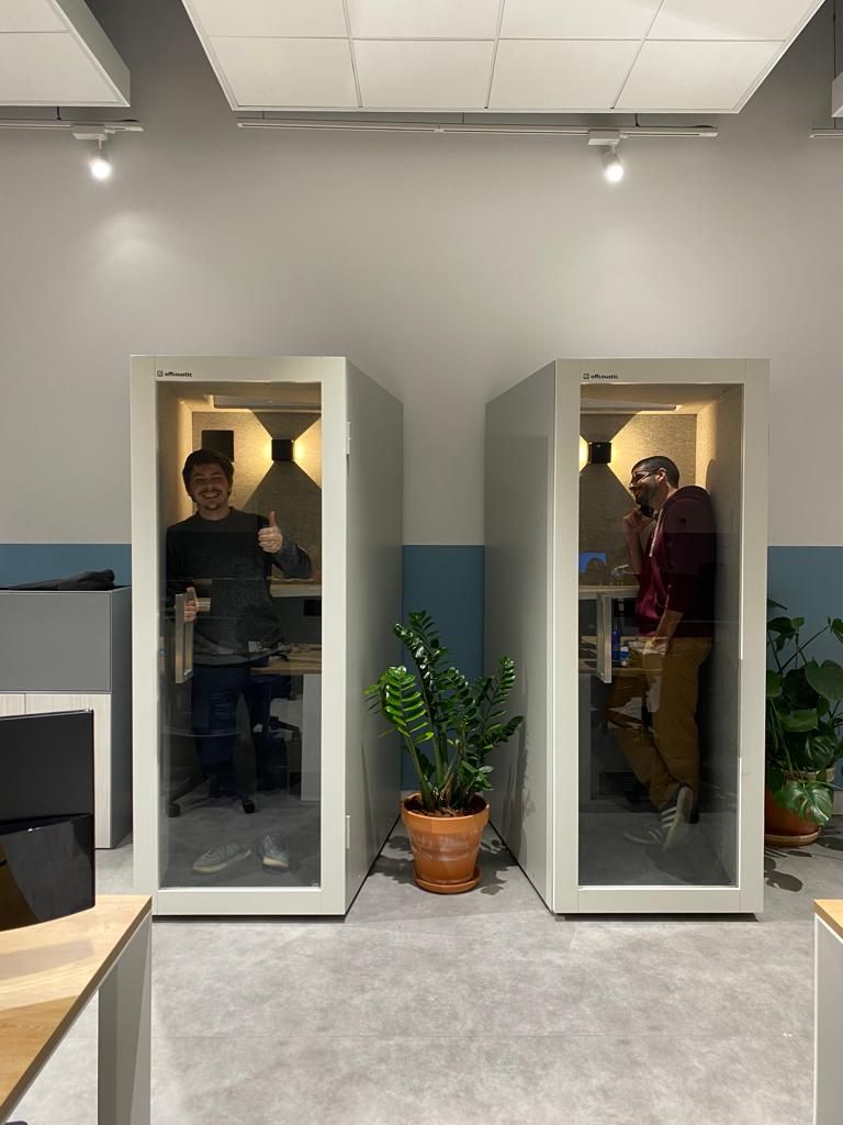 Two people using Offcoustic phone booths, one giving thumbs up