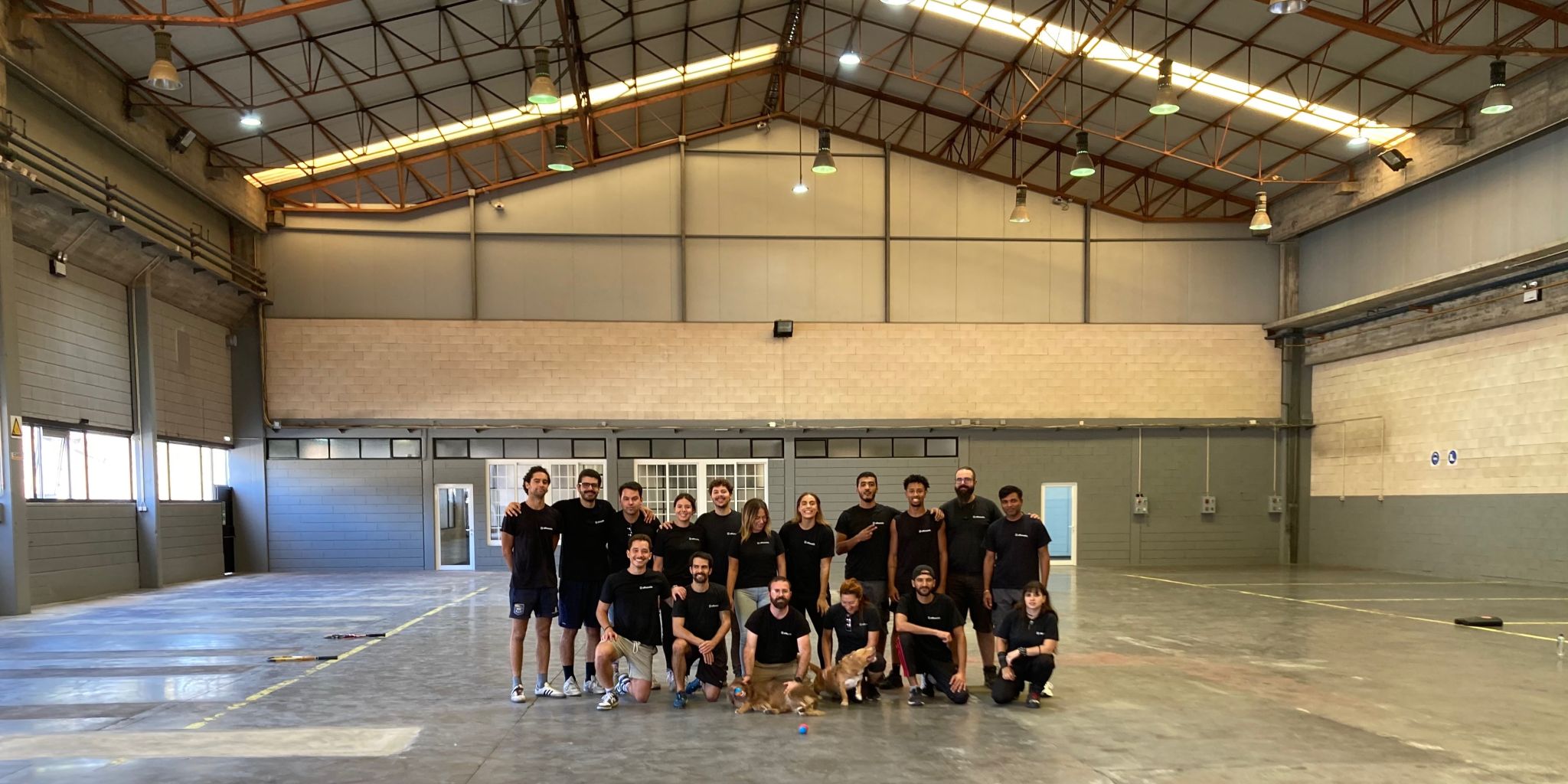 Full team photo in a large warehouse, everyone in matching black shirts